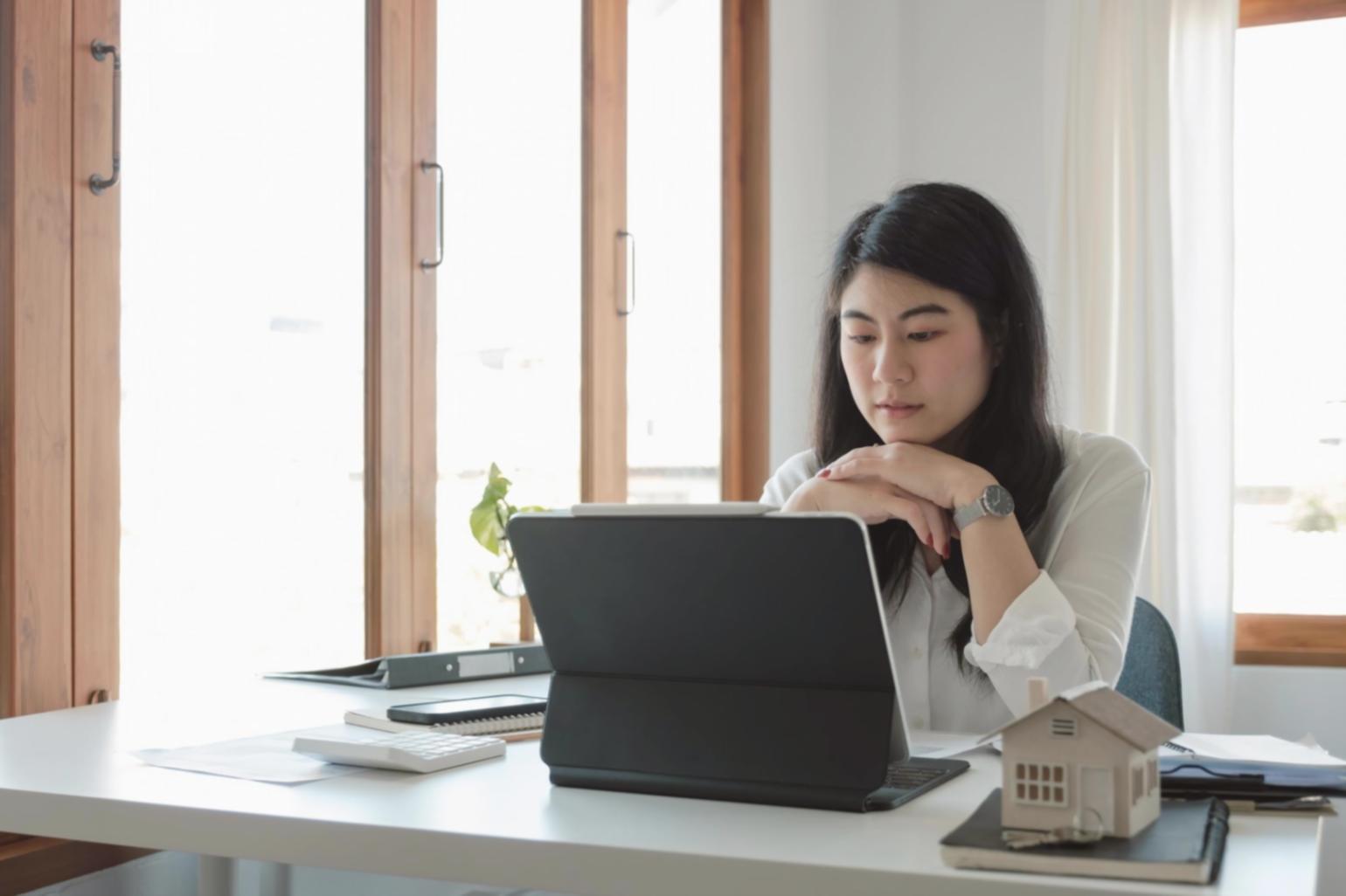 Finanzplanung am Laptop mit Taschenrechner und Unterlagen